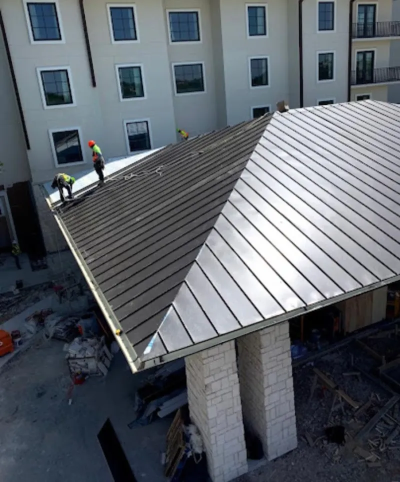 Crew installing standing seam metal roof panels on a commercial project in Town of Pecos